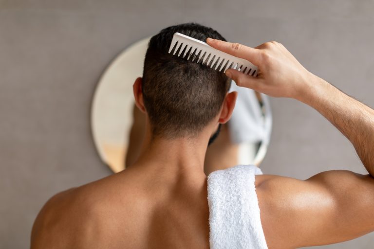 Hombre peinándose frente al espejo del baño tras un injerto capilar en Torreguadiaro